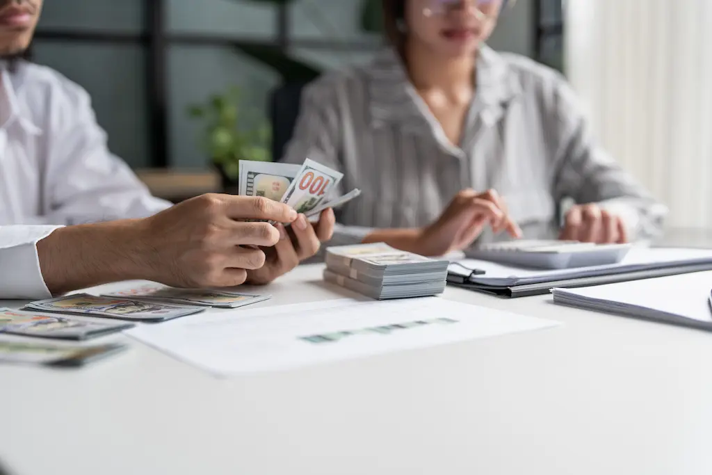 Business professional counting a large stack of US dollar bills.