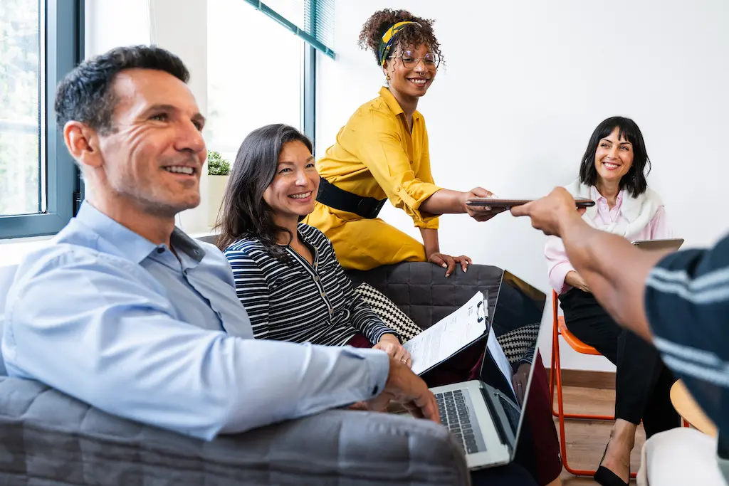 Three business professionals collaborating and looking at a laptop in an office.